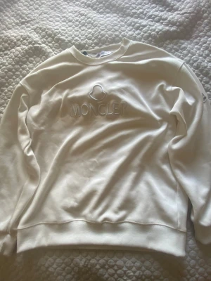 Vit sweatshirt från Moncler - Snygg vit sweatshirt från Moncler med broderad logga på bröstet. Tröjan har rund halsringning och långa ärmar. Perfekt för dig som gillar stilrena och exklusiva plagg. Materialet känns mjukt och bekvämt mot huden.