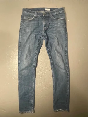 Blå skinny jeans Tiger of Sweden - Snygga blå skinny jeans från Tiger of Sweden med klassisk femficksdesign och ljus tvätt. Jeansen har en smal passform och är tillverkade i mjukt denimtyg. Perfekta för en trendig och avslappnad look.