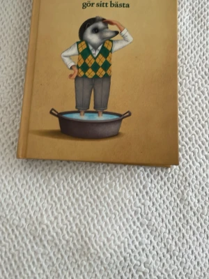 Jefferson gör sitt bästa bok - En illustrerad bok med hård pärm från Lilla Piratförlaget. Omslaget har en tecknad figur med djurhuvud i väst och byxor, stående i en gryta. Boken är på svenska och riktar sig till unga vuxna och tonåringar.