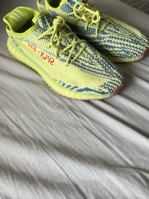 Boost 350 V2 Semi Frozen Yellow - Säljer ett par Boost 350 Semi Frozen Yellow med stickad ovandel i gul och blå, röda detaljer på sidan och genomskinlig sula. Skriv om du är intresserad och dessa är bara använda Max 3 ggr ganska sparsammt. Kartong tillkommer ej och pris kan även diskuteras😁