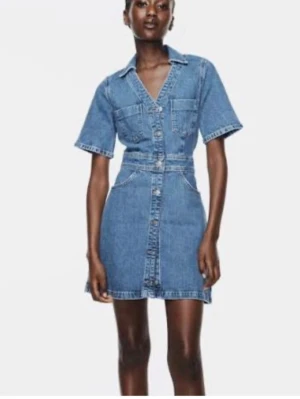 Kort jeansklänning med knappar - Snygg kort jeansklänning från Zara med v-ringning, korta ärmar och knappar framtill. Helt oanvänd med prislapp kvar. Klänningen har två bröstfickor fram. Super fint till sommaren🫶