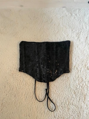 Svart paljettkorsett med snörning - Snygg svart korsett täckt med glittrande paljetter och snörning i ryggen för justerbar passform!🌸