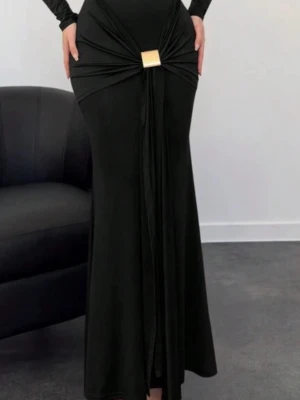 Svart långklänning med gulddetalj - Elegant svart långklänning med lång ärm och markerad midja. Klänningen har en snygg guldfärgad detalj framtill och drapering som ger en cool siluett. Tillverkad i ett mjukt, stretchigt tyg som sitter snyggt på kroppen.