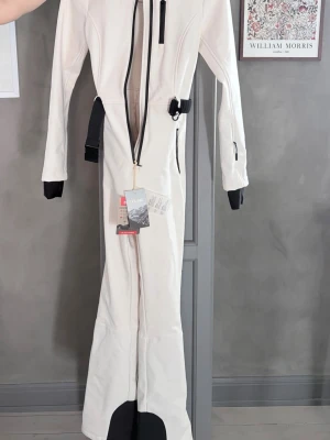 Vit skidoverall från ZARA SKI - HELT NY - Väldigt snygg vit skidoverall (skidkläder) från Zara/Zara Ski. Svarta detaljer. Helt oanvänd med prislappen kvar. Nypris 1 395 kr. Storlek XS.  Säljer på grund av att den tyvärr är för liten för mig (och missade returdatum). 