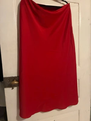 Röd sidenliknande kjol från Lindex - En enkel och stilren röd sidenliknande kjol från Lindex. Kjolen har en rak passform och är gjord i ett mjukt, lätt material som ger ett snyggt fall. Perfekt att matcha med en crop top eller stickad tröja för en trendig look.