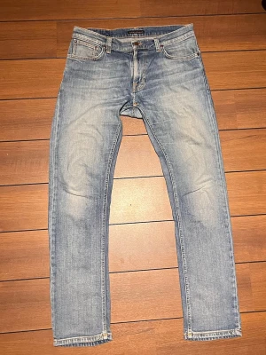 Nudie jeans vintage  - Pris kan diskuteras.                                                        Ett par feta Vintage Nudie jeans i en ljusblå urtvättad naturlig wash efter många års användning. Storlek 33/32..  Lite ut töjda i midja så passar även w34. Modellen heter Thinn Finn och är en straight/ slim passform med organisk bomull.                                                                           2 Små lagningar mellan benen. Syns inte när dem används. Annars fel fria.