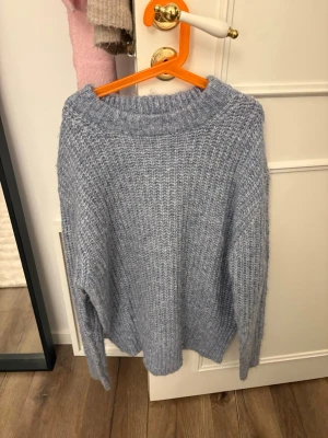 Blå stickad tröja från 157 - Säljer en blå stickad tröja från 157 i storlek XS. Tröjan har en grov ribbstickning och rund halsringning. Perfekt för att hålla sig varm under kyliga dagar. Materialet känns mjukt och fluffigt, vilket gör den extra bekväm att bära.