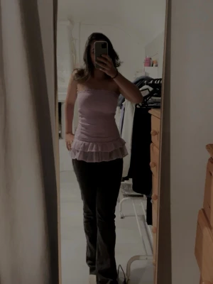 Ljuslila volang tubtopp - Säljer en ljuslila tubtopp med volang nedtill. Toppen är ärmlös och har en bandeau-form som sitter tight över kroppen. Perfekt för dig som gillar en feminin och trendig stil. Inga fläckar eller hål, använd bara en gång och köptes för 300