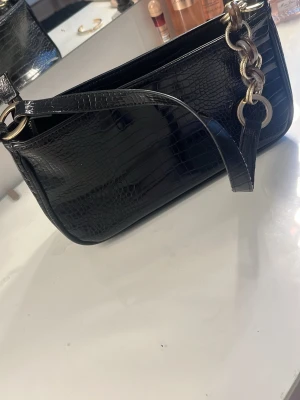 Svart handväska  - Snygg svart handväska i konstläder. Vet tyvärr inte märket då det är min mammas gamla. Får plats med väldigt mycket saker i och den har en dragkedja så man kan stänga! (Står ej för frakt)