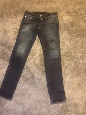 Replay anbass - Snygga mörkblå  Replay anbass med klassisk femficksdesign och snygga detaljer. Jeansen har en lätt tvättad look och är tillverkade i stretchigt denimtyg för skön passform. Perfekta för dig som gillar en vardaglig men även uppklädd. Dom har även en stilren design.