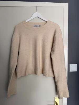 Beige stickad tröja från Weekday - Boxig och croppad passform, tröjan är i storlek L men skulle säga att den är mer som en M i storleken. Den är lite beige gul med inslag av rosa.