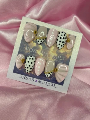 Bijou (M);Short Almond - Snygga press-on naglar i mandelform från Von Juan Nails. Mix av ljusrosa, nude och vita naglar med svarta prickar, guldfärgade kedjedetaljer och vita prickar. Handgjorda och unika, perfekta för dig som vill ha en trendig och lekfull look.