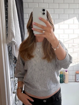 Ljusgrå stickad tröja med ballongärm - Mysig ljusgrå stickad tröja med ballongärmar och rund halsringning från Ellos i storlek S. Tröjan har ribbade muddar vid ärmslut och nederkant, använd ca 3 gånger 💕