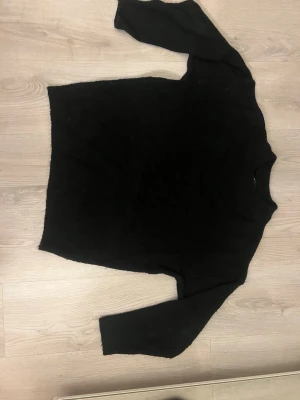 Svart stickad tröja  - En enkel och stilren svart stickad tröja med rund hals och långa ärmar. 