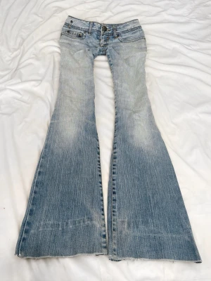 Ljusblå lågmidjade bootcut  jeans med slitningar - Sååå sjukt snygga vintage superlågmidjade jeans bootcut jeans! Säljer eftersom dem inte passar därför har jag ingen bild på😩😩🙏🏼🙏🏼😭 Midjemått: 36 cm Innebenslängd: 78 cm! 