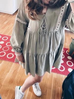 Grön kort klänning från Zara  - Supersöt grön kortklänning med volanger och vita spetsdetaljer längs ärmar och bröst. Klänningen är använd ett fåtal gånger och är i bevarat skick! Supersöt💚