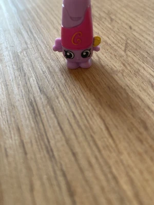 Lila Shopkins figur med ögon - Söt liten Shopkins figur i plast, lila och rosa med stora tecknade ögon och ett gult handtag på sidan. Figurerna har en lekfull design och är perfekta för samlare eller som dekoration. Passar bra till dig som gillar små samlarprylar. Den går inte att köpa längre, återförsäljnings pris är 80-100kr