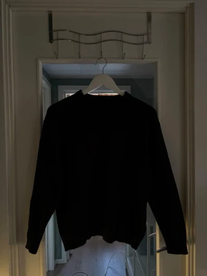 Stickad tröja från Zara - En enkel svart sweatshirt med rund hals och långa ärmar. Tröjan har en klassisk passform och ribbade muddar vid ärmslut och nederkant. Perfekt för en avslappnad och stilren look. OBS, denna är liten i storleken.