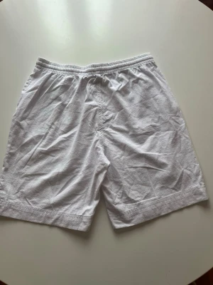 Vita Soyaconcept shorts med snörning - Snygga vita shorts med elastisk midja och snörning framtill.alrig använts. De har en avslappnad passform och är tillverkade i ett lätt bomullstyg, perfekta för varma dagar. Shortsen har fickor på sidorna och en enkel, stilren design.helt nya parfect till sommaren.