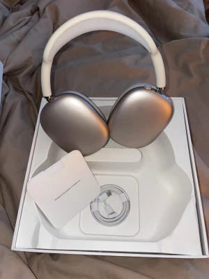 Apple AirPods Max starlight hörlurar - Snygga Apple AirPods Max i silver med en stilren design. Over-ear-modell med mjuka öronkuddar och justerbart huvudband i vitt mesh-tyg. Tillverkade i aluminium och rostfritt stål för en premiumkänsla. Perfekta för musik, gaming eller film.