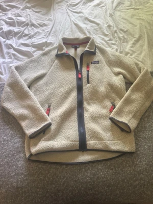 Beige fleecejacka från Patagonia - Säljer en beige fleecejacka från Patagonia med dragkedja framtill, Storlek M passar mig på 187 bra. Skicket är bra, kanske lite skitig på bilden eftersom den inte är tvättad nydligen men sker tvätt innan försäljning Perfekt att ha och dra på ifall det blir lite kyligt på sommarkvällarna och riktigt skön att ha på sig. Pris inte hugget i sten