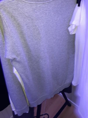 Grå basic sweatshirt - En enkel grå sweatshirt med rund hals och ribbade muddar vid ärmslut och nederkant. Perfekt för en avslappnad stil och lätt att matcha med andra plagg. Tillverkad i mjukt material för extra komfort.