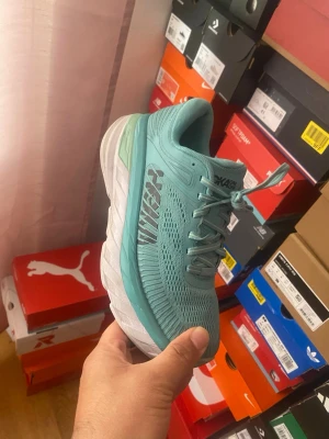  Hoka One One sneakers - Snygga sneakers från Hoka One One med ventilerande mesh-ovandel och tjock, vit sula för extra komfort. Skorna har en sportig look med Hoka-logga på sidan och klassisk snörning. Perfekta för dig som gillar streetstyle och bekväma skor.