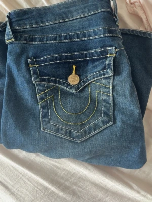 True Religion bootcut jeans blå - Snygga blå bootcut jeans från True Religion med i gul kontrastsöm och fickor med lock 