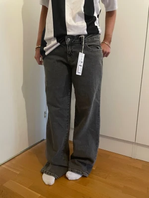 Ultra low Gråa vida jeans från Gina Tricot - HELT NY MED PRISLAPP Säljer ett par gråa jeans från Gina Tricot med lös och rak passform. Jeansen har klassisk femficksdesign, hög midja och långa ben som ger en avslappnad look. Materialet är denim i bomull. Perfekta för en trendig och bekväm stil.