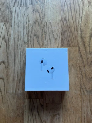 Apple AirPods 3 med laddningsetui - Säljer ett par Apple AirPods 3 i vit färg med tillhörande laddningsetui och originalförpackning. Trådlösa in-ear-hörlurar med stilren design och smidigt laddningsfodral. Perfekta för musik, samtal och träning. USB-C laddningskabel medföljer.