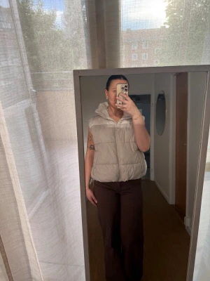 Beige dunväst med huva - Säljer en fluffig beige dunväst med dragkedja.