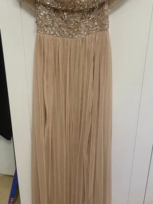 Beige off shoulder långklänning med paljetter - Elegant beige off shoulder långklänning med glittrig överdel täckt av paljetter, och tyllkjol strl L. Har använts en gång och är så gott som ny..