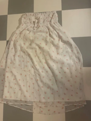 Vit blommig långkjol med snörning - Söt vit långkjol med små rosa blommor och smock i midjan med snörning. Kjolen är i storlek 146/152 men eftersom den är stretchig i midjan så passar den nog till en xxs/xs😁Pris kan diskuteras🥰