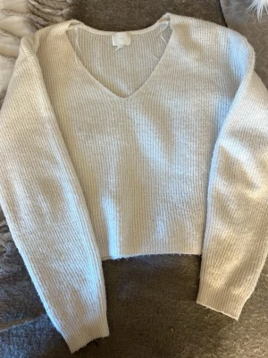 Beige stickad tröja från H&M💞💞 - Mysig beige stickad tröja från H&M med v-ringning och långa ärmar. Tröjan har en croppad passform och ribbstickade muddar vid ärmslut och nederkant. Perfekt för lager på lager och enkel att matcha med jeans eller kjol.