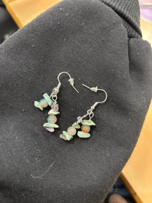 Färgglada örhängen med pärlor och stenar - Unika örhängen med krokar i silverfärg, dekorerade med runda pärlor i orange och blått samt små oregelbundna stenar i grönt och lila. Perfekta för dig som gillar boho-stil och färgglada accessoarer.