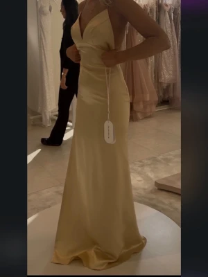 Balklänning  - Säljer min gula balklänning i satin från dressroom i Göteborg. Den har en slits på ena sidan. Den har silvrigt glitter/diamant band i ryggen. Hade denna på min bal, har vissa tecken på användning längst ner då den släpa i marken men inget man tänker på. I strl 2, motsvarar 32/34, XS/S skulle jag säga. Jag är ca 170 cm, sista bilderna är från dressrooms modeller. Nypris 3990kr 