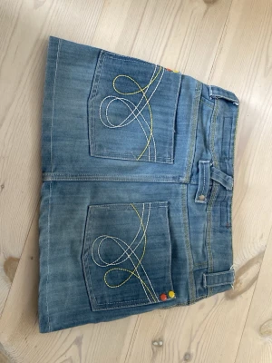 Ljusblå miniskirt  - Blå jeanskjol med jätte fina detaljer som broderi och knappar. Liten i storleken 