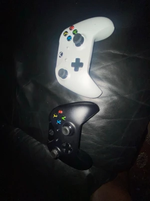 Xbox Series handkontroller svart & vit - Två Xbox Series handkontroller, en i matt svart och en i vit. Båda har klassisk ergonomisk form, färgade knappar och greppvänligt material i plast. Perfekt för gaming med vänner eller solo, kompatibel med Xbox Series X/S och PC.