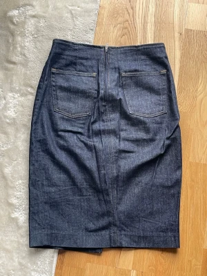 Mörkblå jeanskjol med slits - Mörkblå jeanskjol från Filippa K med slits framtill. Kjolen har knapp och dragkedja i midjan.