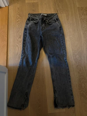 Mörkgråa raka jeans från NA-KD - Snygga mörkgråa raka jeans från NA-KD i tvättad denim. Jeansen har medel hög midja, klassisk femficksdesign och slitsar nertill på benen. Jeansen är även nerkortade litegrann till en passform för 155 cm lång person.