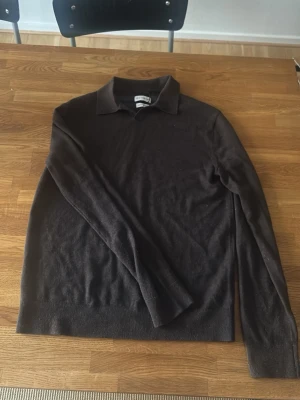 Mörkbrun merinotröja These Glory Days - Snygg mörkbrun stickad tröja från These Glory Days i mjuk superior merinoull. Tröjan har klassisk krage och långa ärmar, perfekt för dig som gillar stilrena och tidlösa plagg. Passar till många olika looks och är riktigt skön att bära.