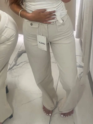 Beiga raka jeans från ONLY -  Superfina high waist jeans i wide leg modell (ONLHOPE). Färgen är krämvit/ecru och passar till allt.  Storlek: W26/L32 (EU 26/32) – ca XS/S. Skick: Oanvända, men lappen finns inte kvar.  Säljer då de tyvärr inte kommer till användning. Skriv vid frågor eller intresse!                                                                    