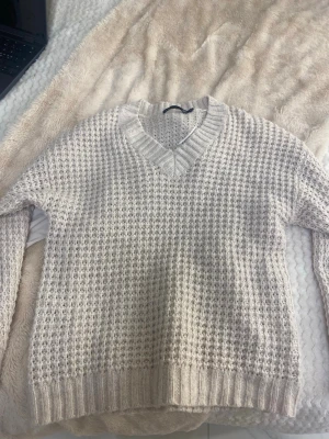 Beige stickad tröja från 157 - Säljer en beige stickad tröja från 157 i storlek XS. Tröjan har ett grovt stickat mönster och en djup v-ringning med bred ribbstickad kant. Långa ärmar och ribbade muddar vid ärmslut och nederkant. Perfekt för lager-på-lager och chill dagar.
