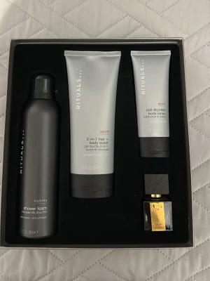 Rituals presentbox med duschprodukter - Snygg presentbox från Rituals med duschskum, 2-i-1 hår- och kroppstvätt, body lotion och en liten parfym. Produkterna har stilrena förpackningar i svart och silver. Perfekt för dig som gillar fräscha och sportiga dofter.