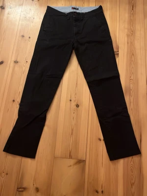 Svarta chinos  - Snygga svarta chinos från dressman med rak/slim passform. Byxorna har framfickor, bälteshällor och två bakfickor med knapp. Tillverkade i ett mjukt bomullsmaterial. 