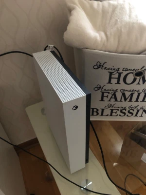 Xbox One S vit spelkonsol - Säljer en Xbox One S spelkonsol i stilren vit färg med svart detalj på sidan. medföljer gör en matchande vit trådlös handkontroll. Perfekt för gaming och streaming, snygg design.