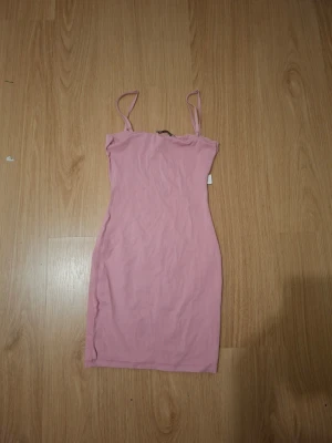 Rosa ärmlös kortklänning - Söt rosa kortklänning med smala axelband och figurnära passform. Klänningen är enkel och stilren, perfekt för varma dagar. Tillverkad i mjukt material som känns bekvämt mot huden.