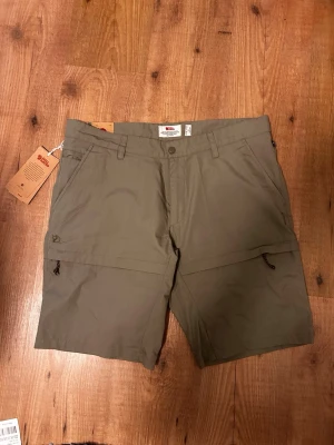 Olivgröna shorts från Fjällräven - Detta är tekniska plagg från Fjällrävens Travel-kollektion, tillverkade i deras lätta och snabbtorkande MT Eco-material (Micro Travel). ( ny priss 1400kr) vårt pris 1000kr. Pris kan diskuteras 