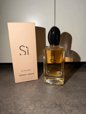Giorgio Armani Sì Eau de Parfum 100 ml - Elegant parfym från Giorgio Armani, Sì Eau de Parfum, i en stilren glasflaska med svart lock och beige kartong. Doften är varm och feminin, perfekt för dig som gillar lyxiga och moderna parfymer. Flaskan rymmer 100 ml och har en exklusiv känsla. KVITTO FINNS