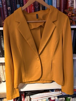 Gul kavaj från Freequent - Snygg gul kavaj från Freequent med klassisk krage och en knapp framtill. Figurnära passform och långa ärmar. Perfekt för dig som vill sticka ut med färg. Tillverkad i ett mjukt tyg som ger en bekväm känsla.